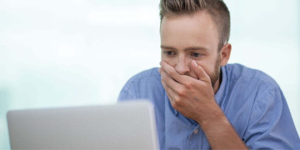 Person reagiert erschrocken auf möglichen Internetbetrug am Laptop